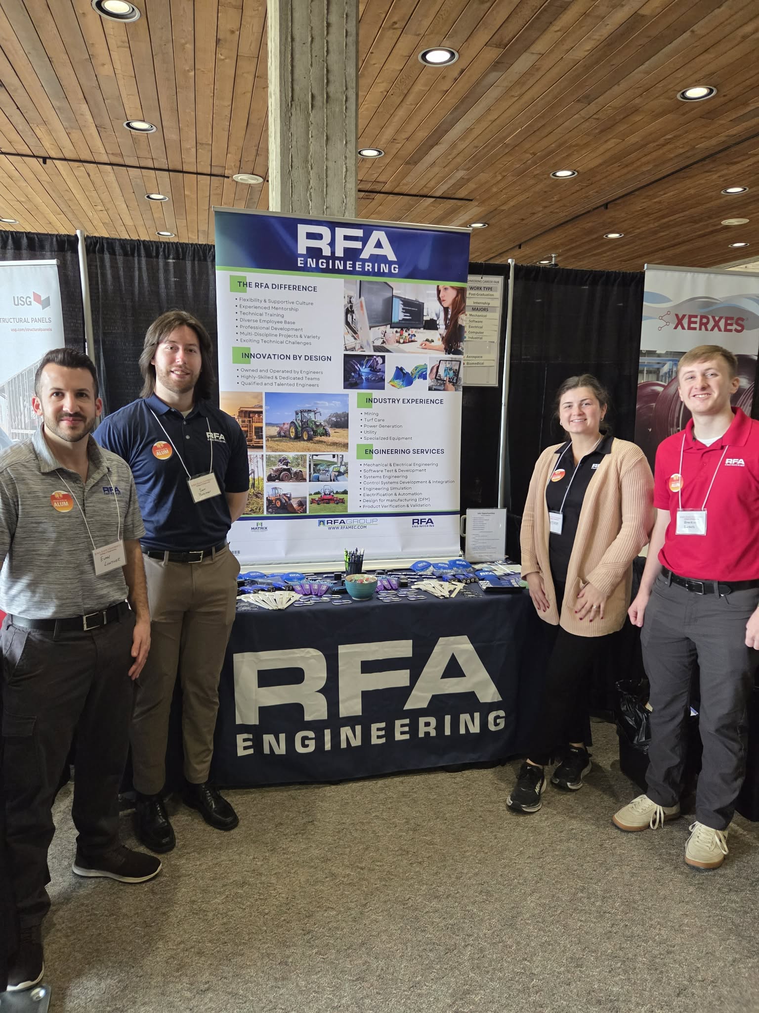 Team members at engineering staffing exhibition booth with promotional materials and display.
