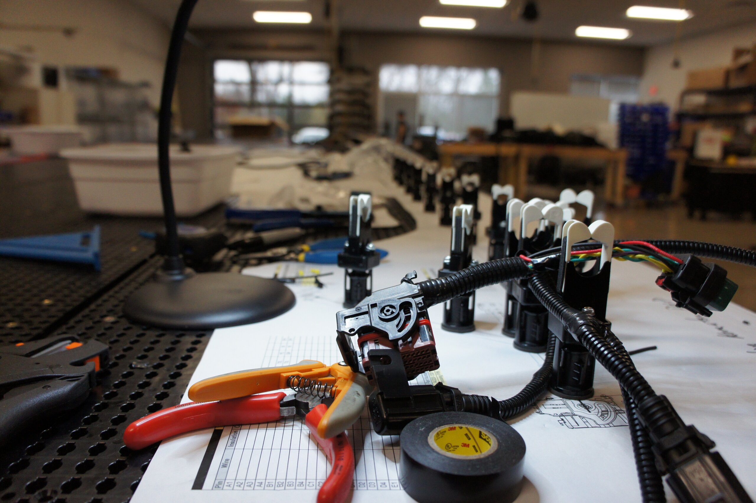 Custom wire harness with soldered connections and heat shrink tubing in prototype assembly workspace