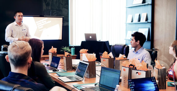 A product launch meeting showcasing a speaker discussing development strategies while attendees review materials.